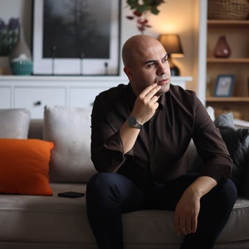 bald man sitting on a sofa in a living room, looking pensive and thoughtful, reflecting on life's challenges