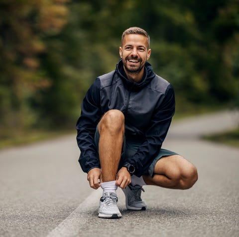 man tying shoelaces before running outdoors, smiling