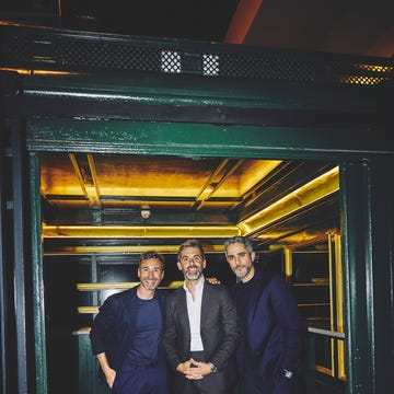 three men posing together in an elevator setting