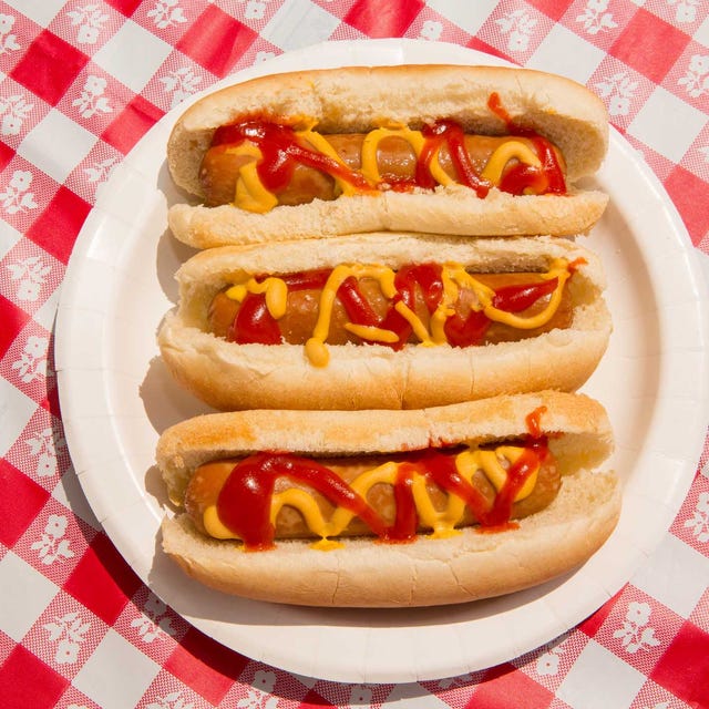 Hot Dogs From Above, Summer BBQ Foods Layout, Hot Dog Buns Overhead america, fourth of july foods hot dogs indulgence and overeating concept for unhealthy eating of junk food, carefree summer picnic, independence day or memorial day backyard bbq july 4th bbq food, no people foods featured are hot dogs with ketchup and mustard and pickles there are patriotic american flag toothpicks as decoration in the festive food paper plates and disposable plastic cups are also on the checkered tablecloth shot during sunny day outdoors on vacation part of a series