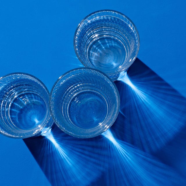 Glasses of Water on Deep Blue glasses of clear protein drinks with long shadow on deep blue colored background view