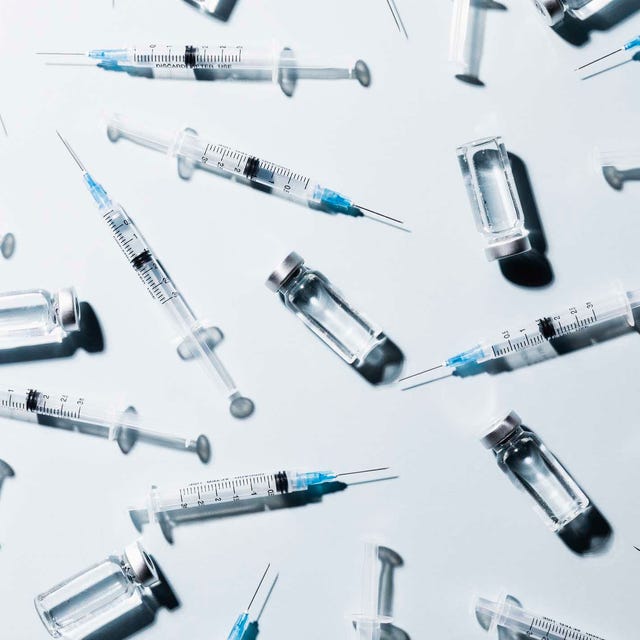 COVID-19 vaccine vials and syringes on white background Syringes and vials arranged on a surface.