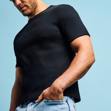 Man posing in casual attire against a light blue background.