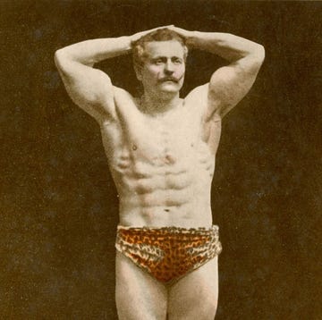 two muscular men posing one with arms raised and the other holding a globe