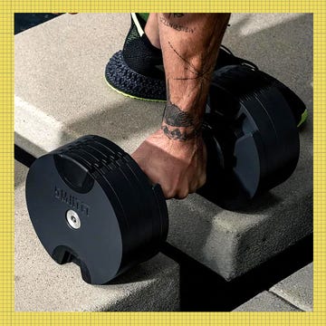 adjustable dumbbells on a workout surface with a person lifting one