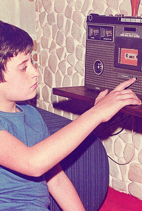 vintage teenage boy playing music on a radio cassette recorder