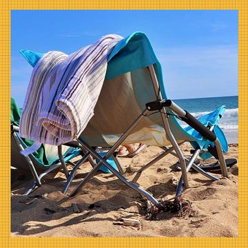 Beach scene featuring folding chairs and a blanket on the sand.