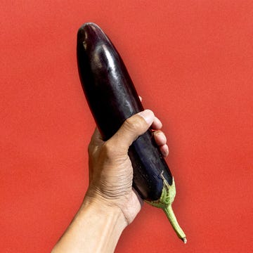 hand holding an eggplant to illustrate masturbation hand holding an eggplant against a red background