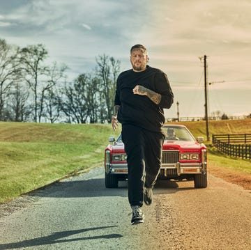 person running alongside a classic car on a rural road