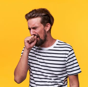 un hombre se tapa la boca al toser