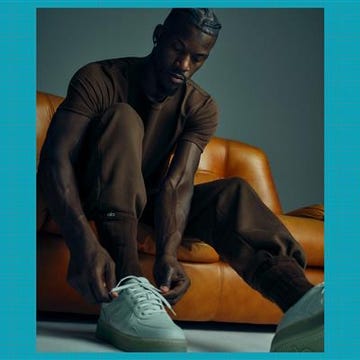 person wearing lightcolored sneakers while sitting on an orange sofa