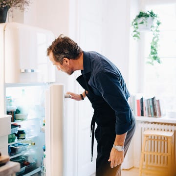 mature man looking into refrigerator while standing at kitchen