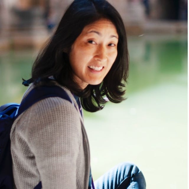 person sitting near a water body in an ancient architectural setting