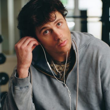 young person wearing a hoodie and earphones in a gymlike setting