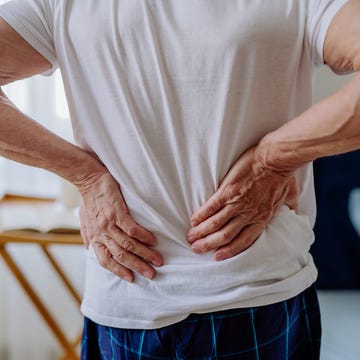 senior man having back pain, standing in his bedroom