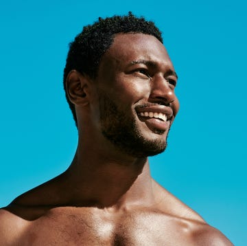 handsome, happy and confident black man posing against a perfect and clear blue sky copy space background. beauty closeup of the face and head of a young african american male outside from below