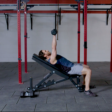 person performing a dumbbell exercise on an adjustable bench in a gym person performing a dumbbell exercise on an adjustable bench in a gym