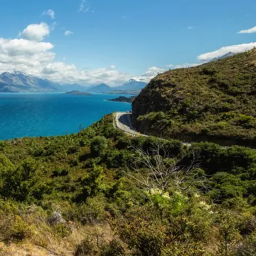 scenic view of a mountainous landscape by a lake with a winding road